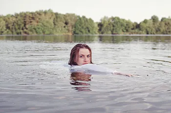 Junge Frau schwimmend im See mit Blick zur Kamera